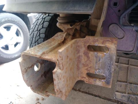 1996 Ford Bronco - Close-up of a heavily rusted bumper bracket, showing its mounting points and wear.