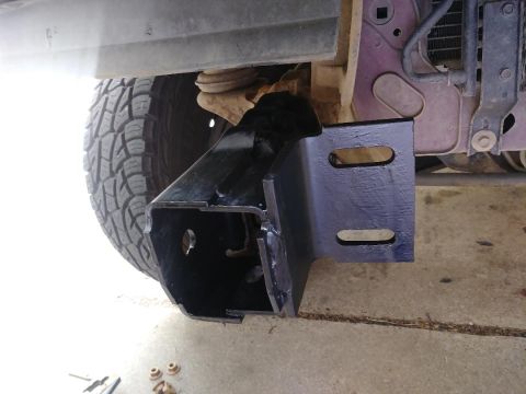 1996 Ford Bronco - A new bumper bracket is attached to the vehicle's frame, showing part of the tire and suspension.