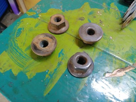 1996 Ford Bronco - Four lug nuts are laid out on a painted surface, showing signs of rust and wear.