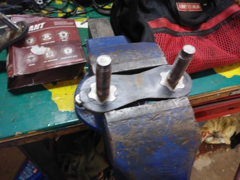 1996 Ford Bronco - A metal component, possibly for a vehicle bumper installation, is held firmly in a vise for work.