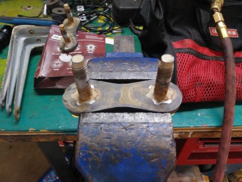 1996 Ford Bronco - A metal part with threaded bolts is secured in a vise for work.