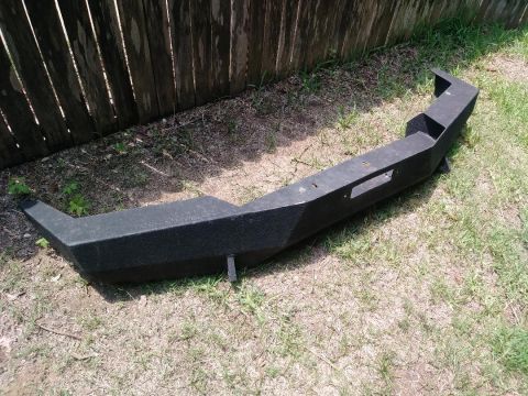 1996 Ford Bronco - Aftermarket front bumper shown resting on grass in front of a wooden fence.