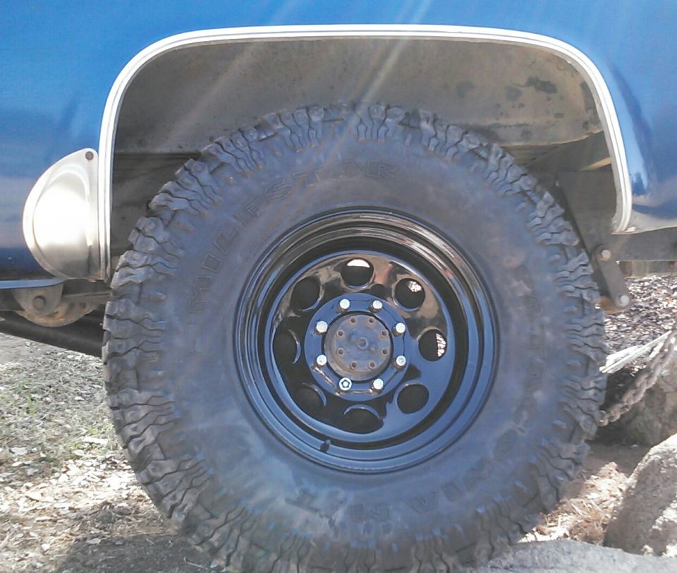 Close-up of a blue truck's rear wheel and fender with off-road tires