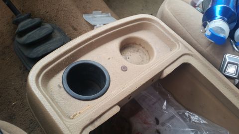1985 Ford Bronco - Interior view of a vehicle's center console, showing cup holders and a gear shifter boot.