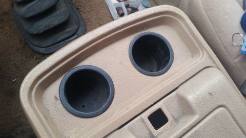 1985 Ford Bronco - Interior shot of a vehicle's center console, showing cup holders and a gear shift boot.
