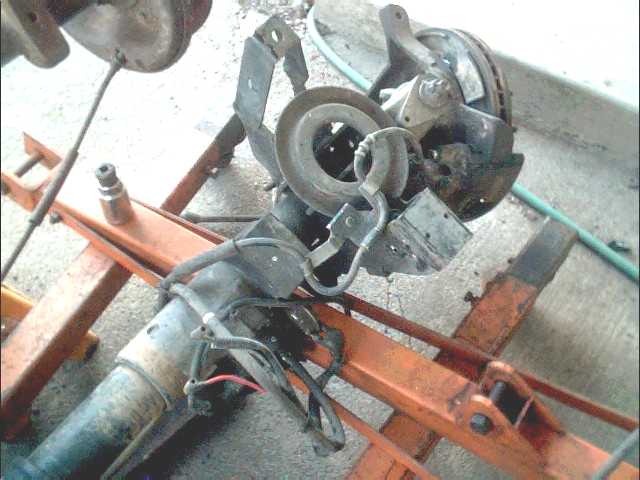 Front suspension assembly with brake rotor and caliper, mounted on an orange engine hoist