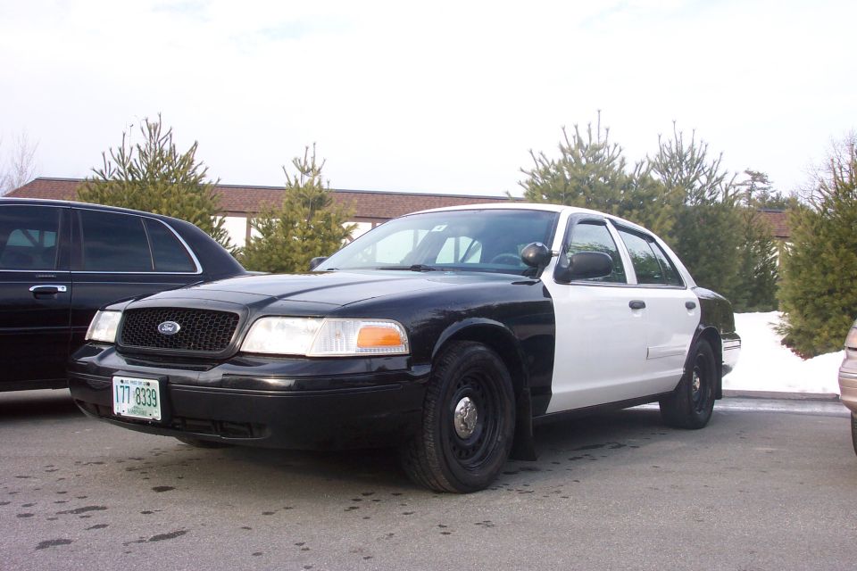 Two-tone police car, black front and white rear, parked on asphalt