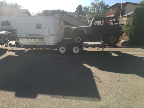 1992 Jeep Wrangler - Trailer hauling a Jeep Wrangler and a camper down a residential street.