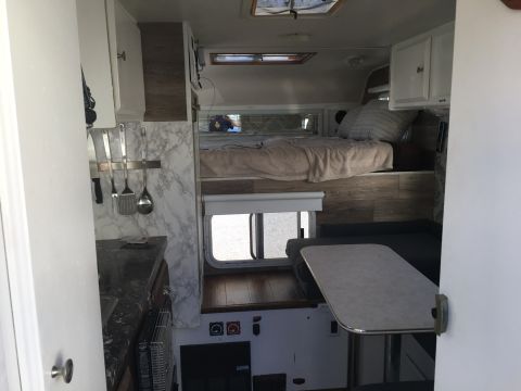 1992 Jeep Wrangler - Interior view of a camper van showing sleeping quarters, a compact kitchen area, and a fold-down table.