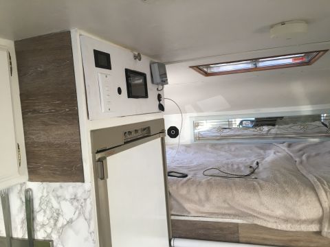 1992 Jeep Wrangler - Interior view of a camper, a bed, refrigerator, and control panel with various switches and screens.