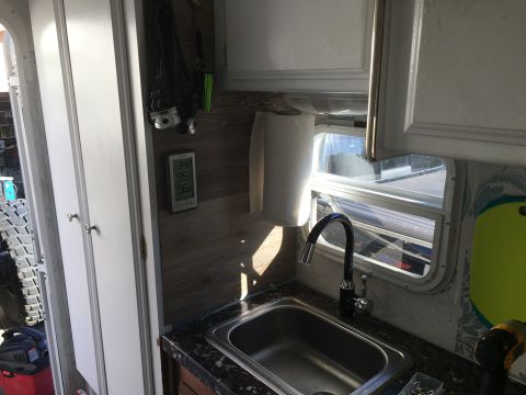 1992 Jeep Wrangler - The interior of a vehicle shows a sink area with a faucet, paper towel dispenser, and a digital thermometer on the wall.