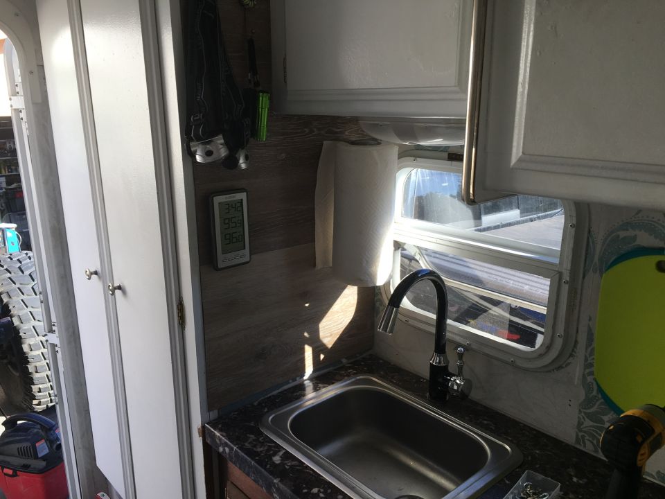 Interior of a vehicle with a sink, faucet, paper towel holder, and digital thermometer