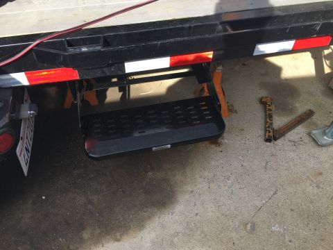 1992 Jeep Wrangler - A close-up view of a retractable step mounted on the side of a trailer, showing its textured surface and reflective safety markings.