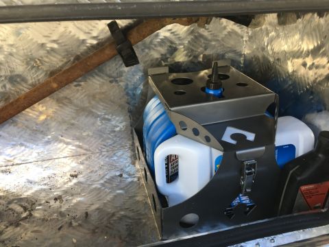 1992 Jeep Wrangler - Organizer with fluids and a rusty bar inside a metal compartment.