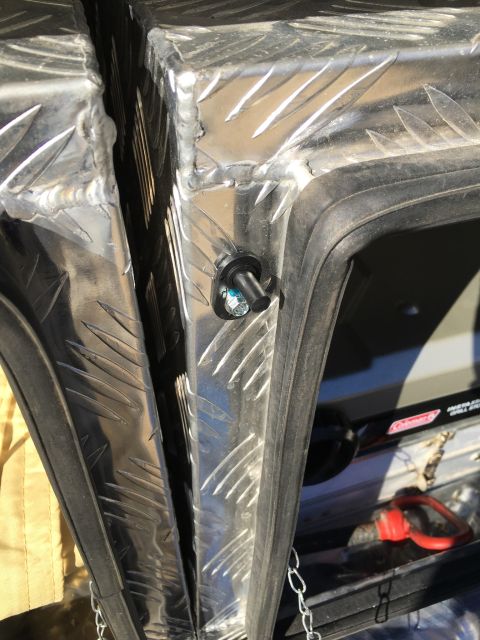 1992 Jeep Wrangler - Detail of a metal door frame with diamond plate texture and a visible latch. A red tow hook is also in view.