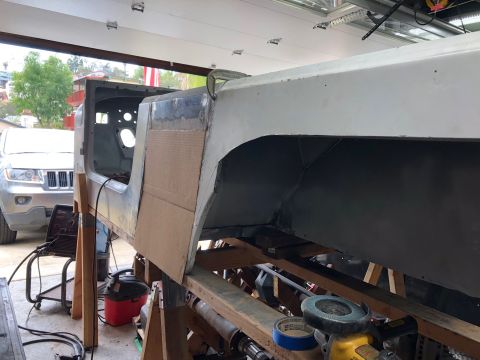 1992 Jeep Wrangler - The body of a Jeep Wrangler is shown in a workshop, supported by wooden stands, with a silver SUV visible in the background.