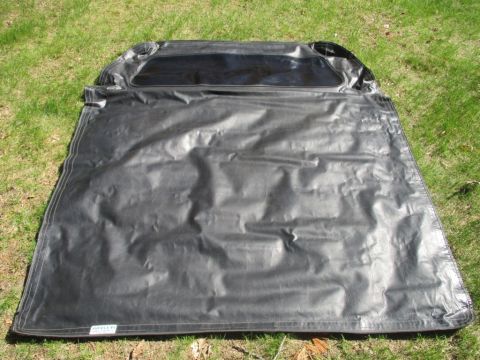 1996 Ford Bronco - A black vinyl soft top, likely for a convertible or SUV, is spread out on a grassy surface.