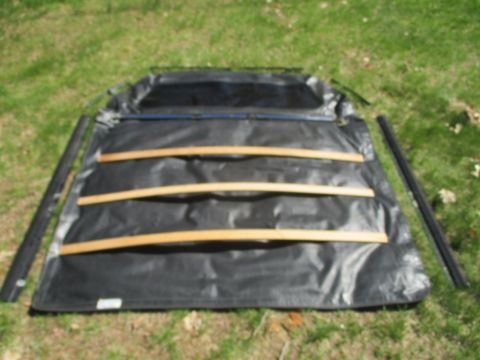 1996 Ford Bronco - A disassembled soft top for a vehicle is laid out on a grassy surface, showing its frame and fabric components.