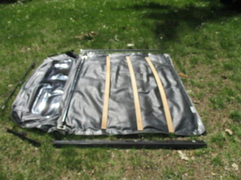 1996 Ford Bronco - Soft top for a vehicle laid out on the grass with its frame and straps.