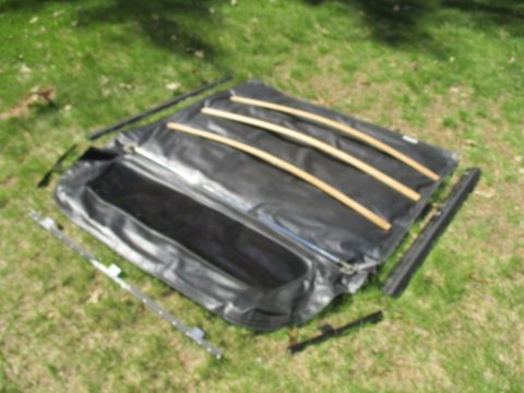 1996 Ford Bronco - A disassembled vehicle soft top is spread out on a grassy area, showing its components.