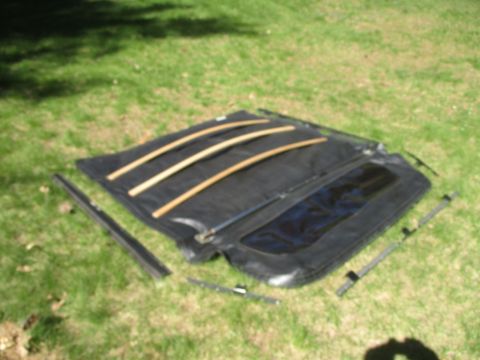 1996 Ford Bronco - A black soft top with wooden support bars is displayed on a grassy surface.
