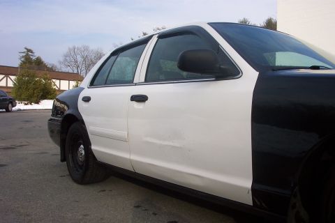 2001 Ford Crown Victoria - A two-tone Ford Crown Victoria is parked on an asphalt lot under a cloudy sky.