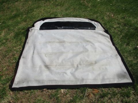 1996 Ford Bronco - A soft top is shown laid out on a grassy surface, appearing to be a replacement part.