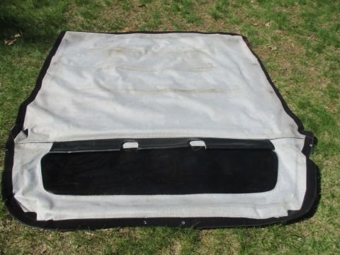 1996 Ford Bronco - A vehicle soft top with a black vinyl window is laid out on a grassy surface.