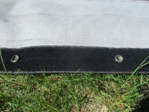 1996 Ford Bronco - Close-up of a soft top edge with grommets, resting on grass. Text from Supermotors.net is visible.