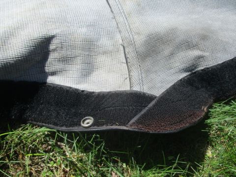1996 Ford Bronco - Detail of a car cover with velcro closure and a metal grommet, resting on grass.