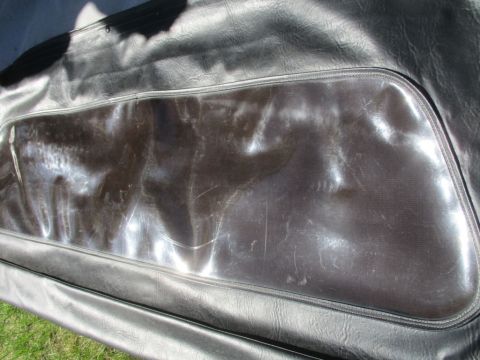 1996 Ford Bronco - Close-up of a scratched black vinyl soft top window with a zipper closure.