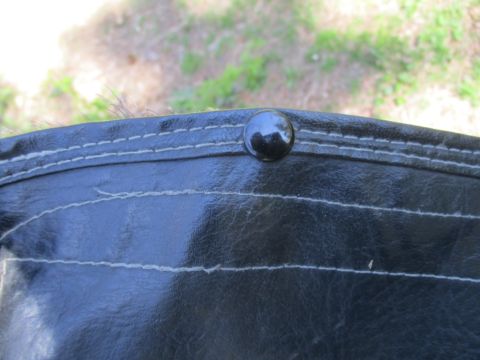 1996 Ford Bronco - Detail of a black vinyl top with visible stitching and a snap fastener, with a Supermotors logo.