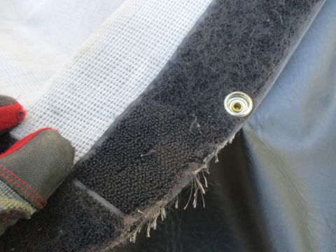 1996 Ford Bronco - A gloved hand touches the velcro and snap fastener on a vehicle's soft top.