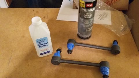 2000 Pontiac Grand Prix - Parts laid out for a car repair, including sway bar end links, primer, and cleaning alcohol.