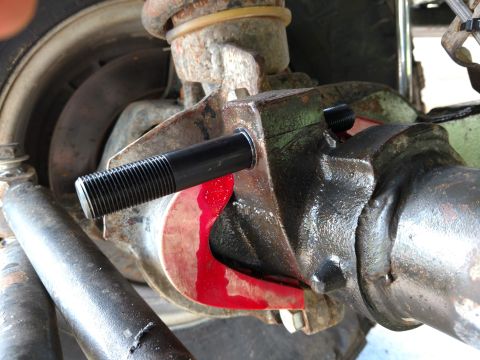 1992 Ford Bronco - Close-up view of a track bar stud being repaired on a vehicle's rear axle, with a red bushing visible.