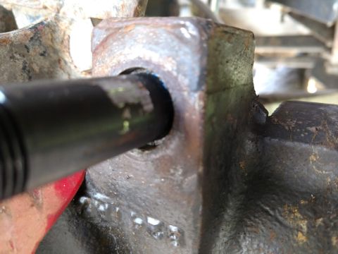 1992 Ford Bronco - Close-up of a rusty metal bracket and a black rod, likely part of a vehicle's suspension system.