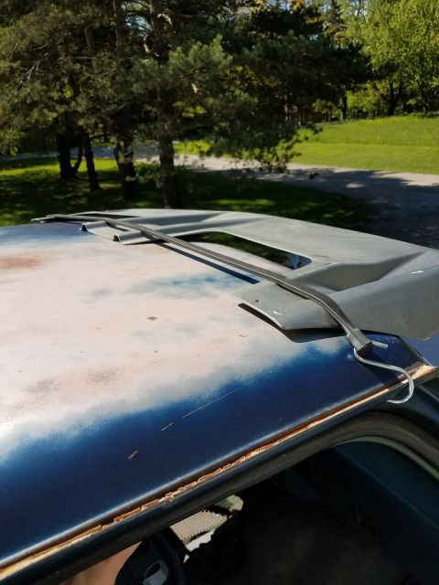 1987 Ford Bronco - The roof of a vehicle is shown with a sunroof opening and signs of wear.