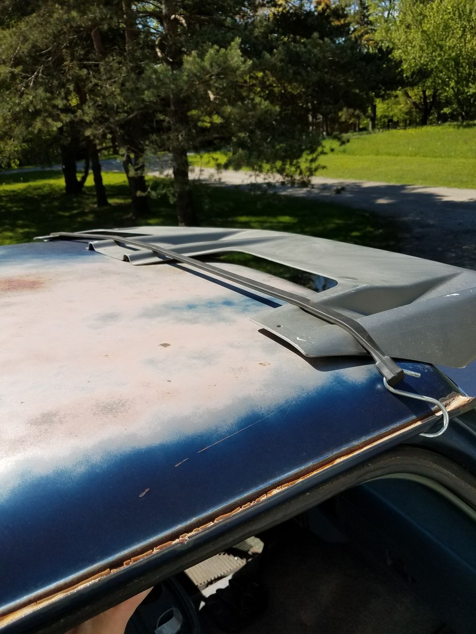 Close-up of a car's roof showing a sunroof opening and weathered paint