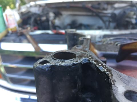 1996 Ford Bronco - A greasy engine bracket is shown in focus, with the vehicle's engine bay blurred in the background.