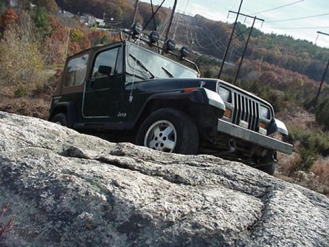 1992 Jeep Wrangler - Jeep Wrangler navigating a rocky trail with power lines in the background.
