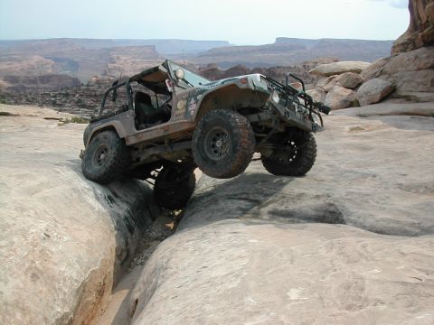 1992 Jeep Wrangler - A modified Jeep Wrangler tackles a challenging rocky terrain in a desert landscape.