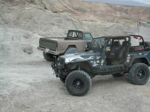 1992 Jeep Wrangler - A 1992 Jeep Wrangler and a pickup truck are parked off-road in a dusty, hilly landscape.