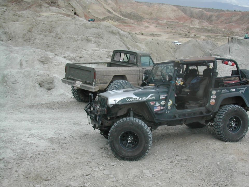 Green 1992 Jeep Wrangler with "WRANGLER" text on hood, parked next to pickup truck