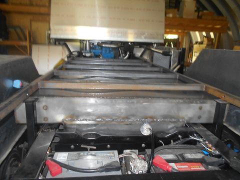 1992 Ford Bronco - The photo shows the undercarriage of a vehicle, focusing on the battery, air compressor, and engine components.