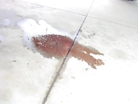 1988 Ford Bronco - A significant fluid leak has stained the concrete surface, indicating a potential issue.