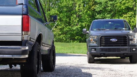 1987 Ford Bronco - A vintage SUV is parked alongside a contemporary pickup truck, with the focus on the rear of the older vehicle.
