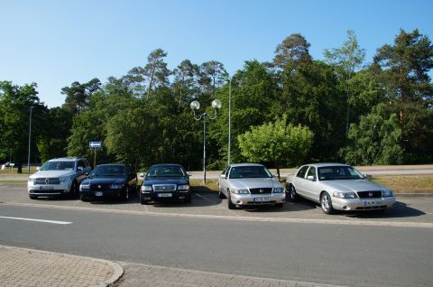 2003 Mercury Marauder - A line of five cars, including a silver 2003 Mercury Marauder, are parked in a lot with trees in the background.