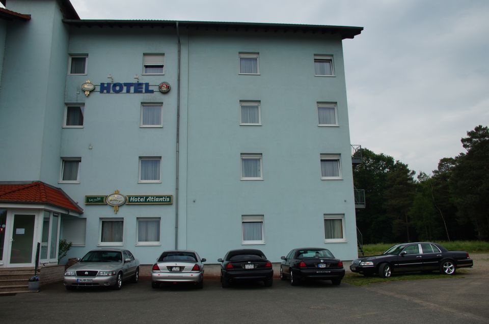 Four sedans parked outside a hotel, one is a dark Ford Crown Victoria
