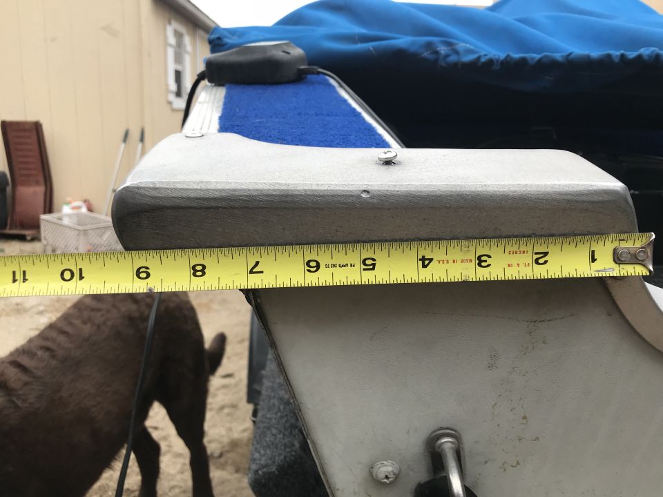 Yellow measuring tape across gray boat part with blue mat.