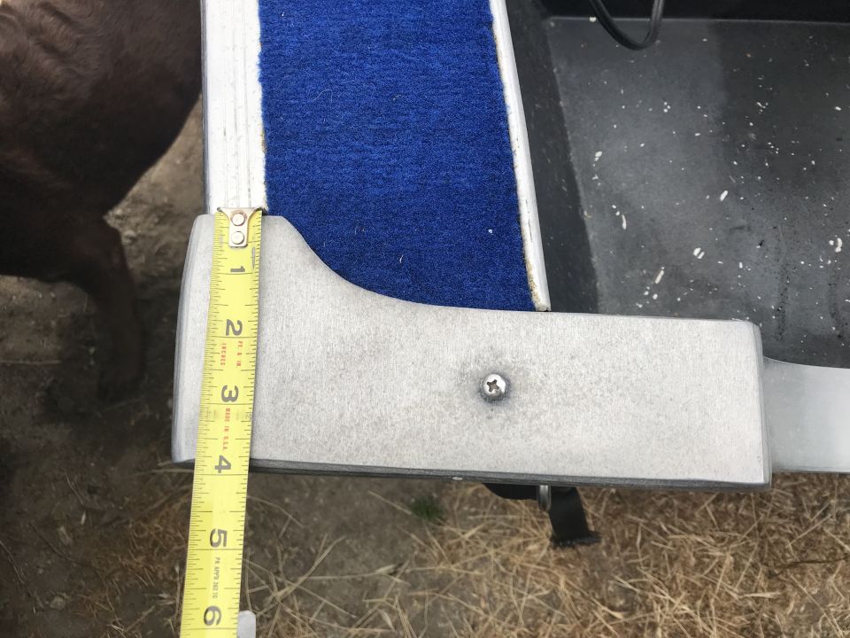 Close-up of a measuring tape showing 5.5 inches against a silver bracket and blue carpet.